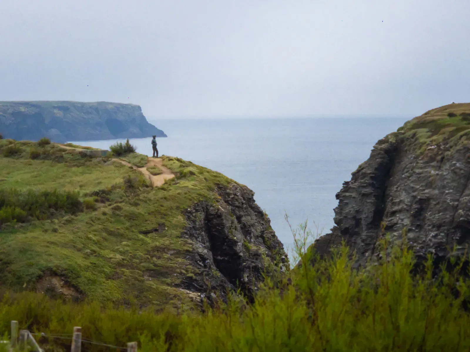 Personne debout au bord d’une falaise face à l’océan - Format paysage