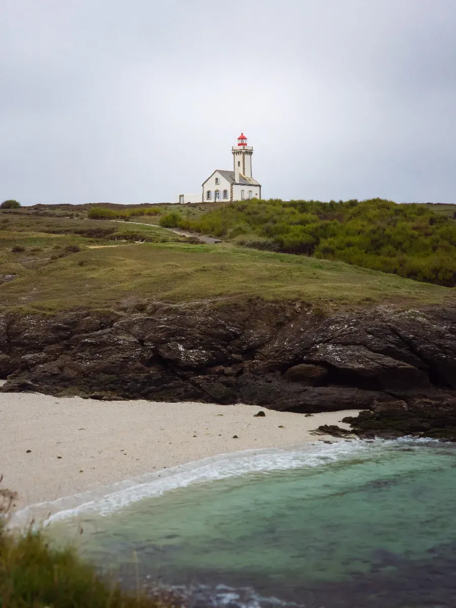 Phare de Belle-Ile-en-Mer dominant une petite plage aux eaux turquoise
