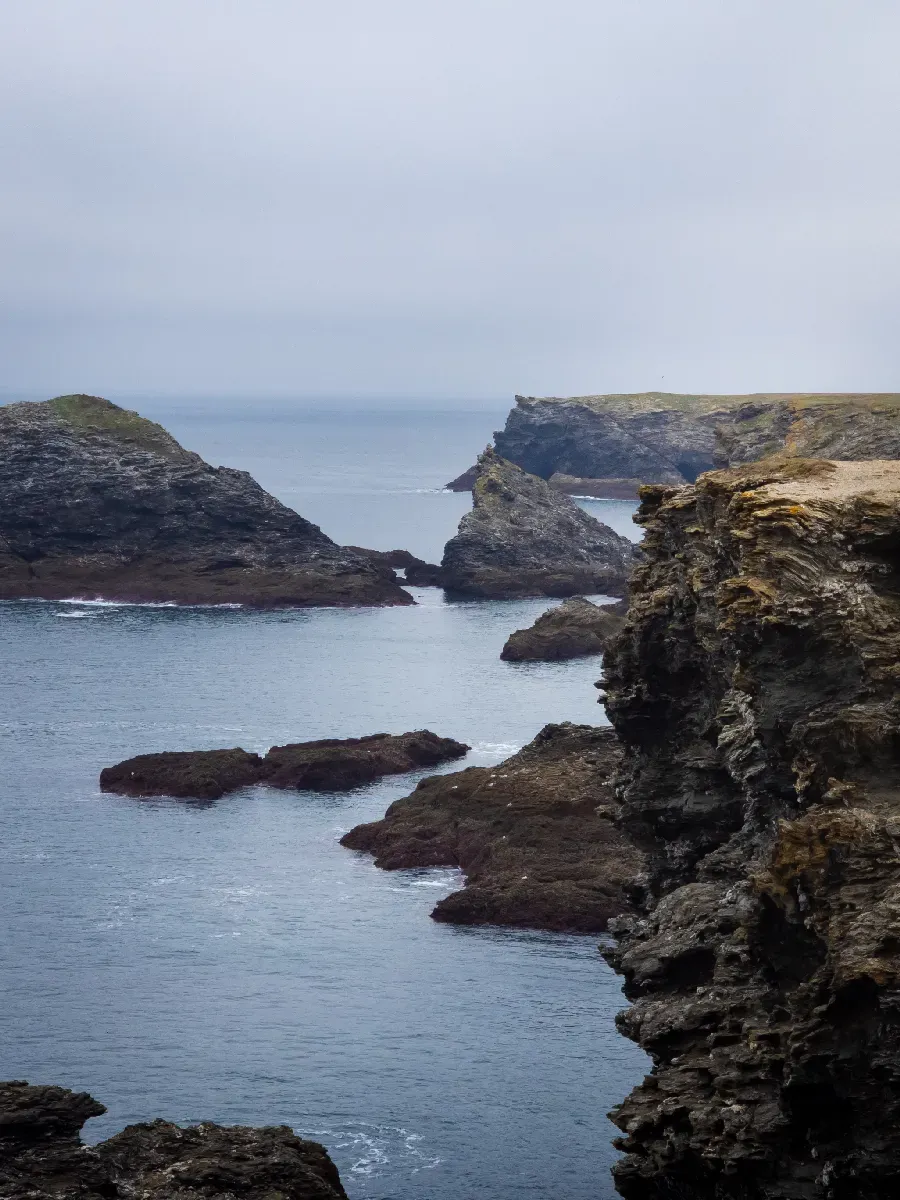 Falaises et formations rocheuses découpant la côte de Belle-Île-en-Mer sous un ciel couvert.
