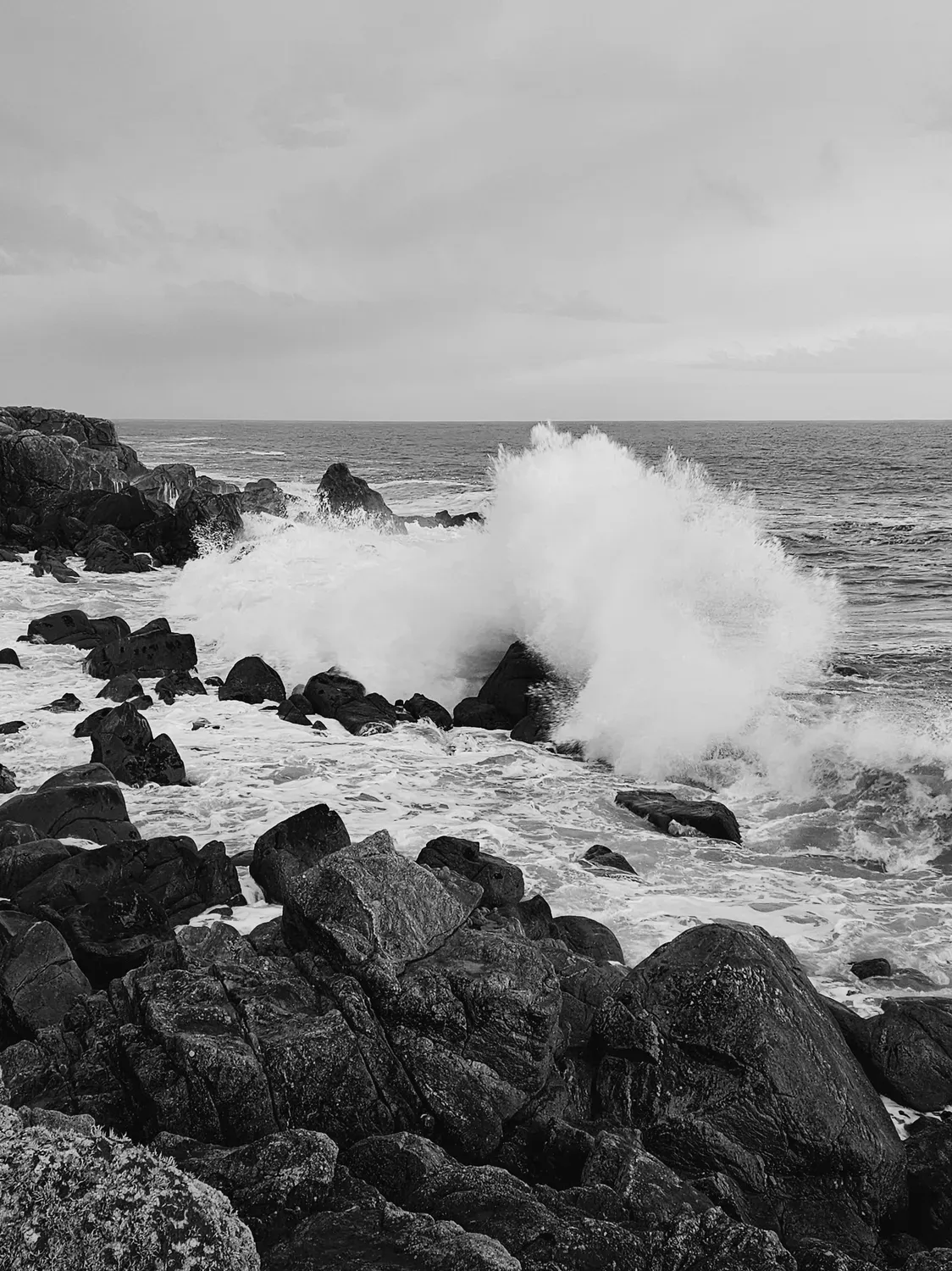 Photographie en noir et blanc de écume sur la digue.