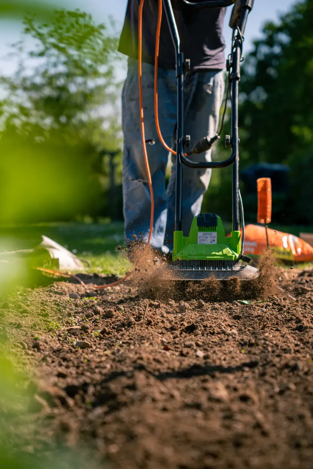 Photographie d un motoculteur travaillant la terre dans un jardin.