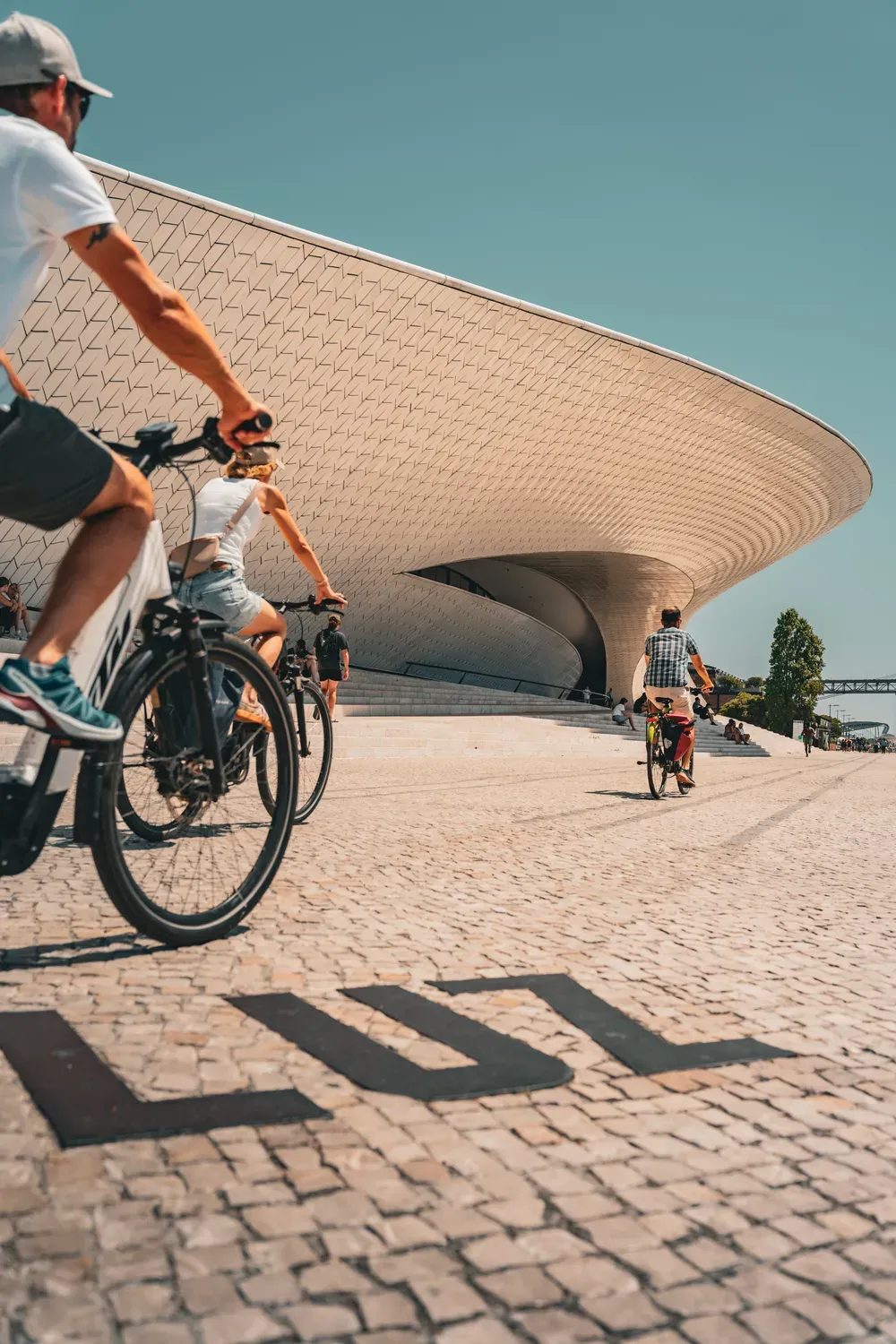 Photographie d un cycliste passant devant l architecture blanche du MAAT a Lisbonne.