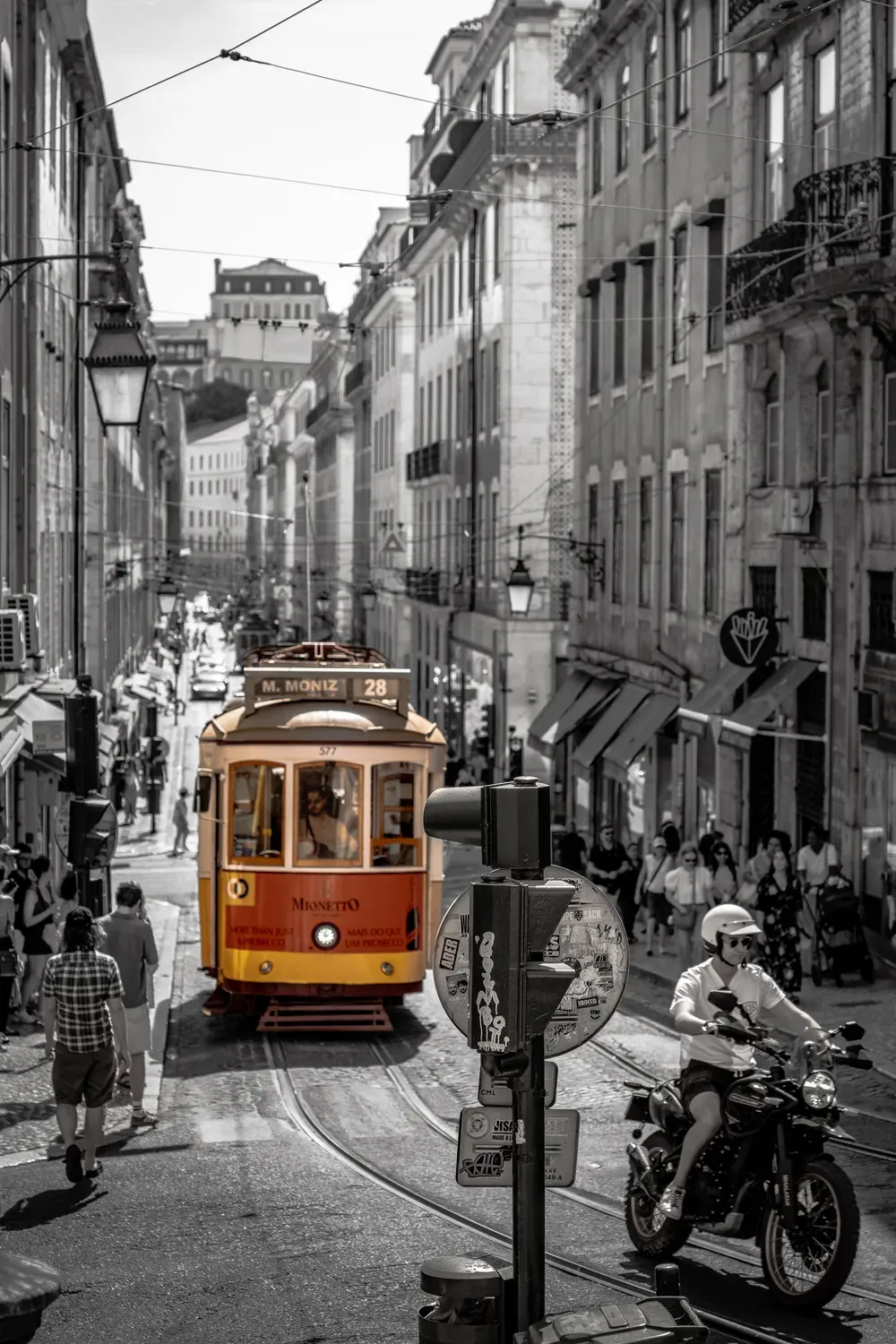 Photographie d un tramway jaune conserve en couleur dans une rue de Lisbonne en noir et blanc.