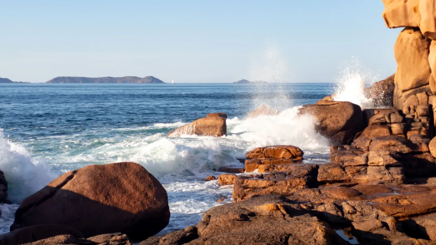 Photographie de vague contre les rochers.