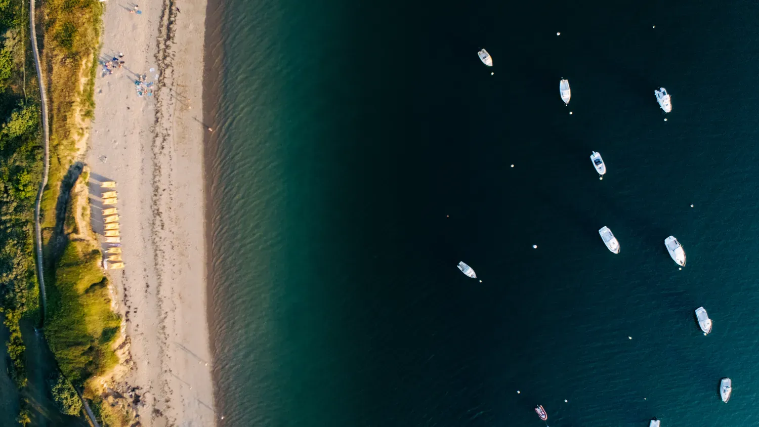 Photographie de bateaux devant la plage.