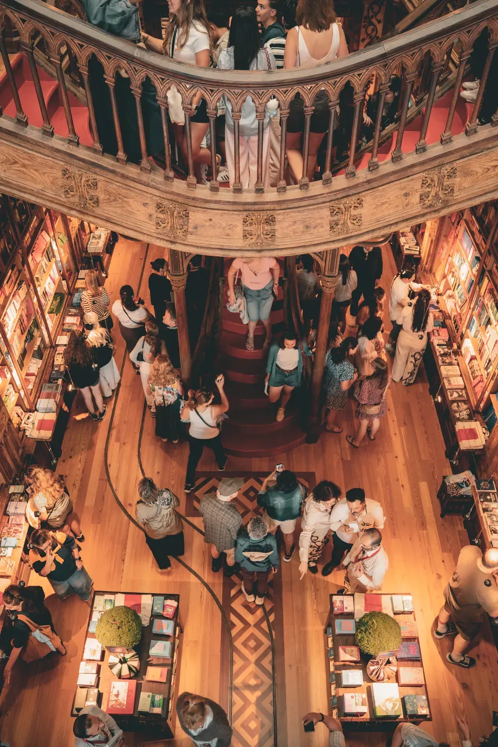 Photographie de l etage d une librairie ancienne avec des visiteurs autour des tables.