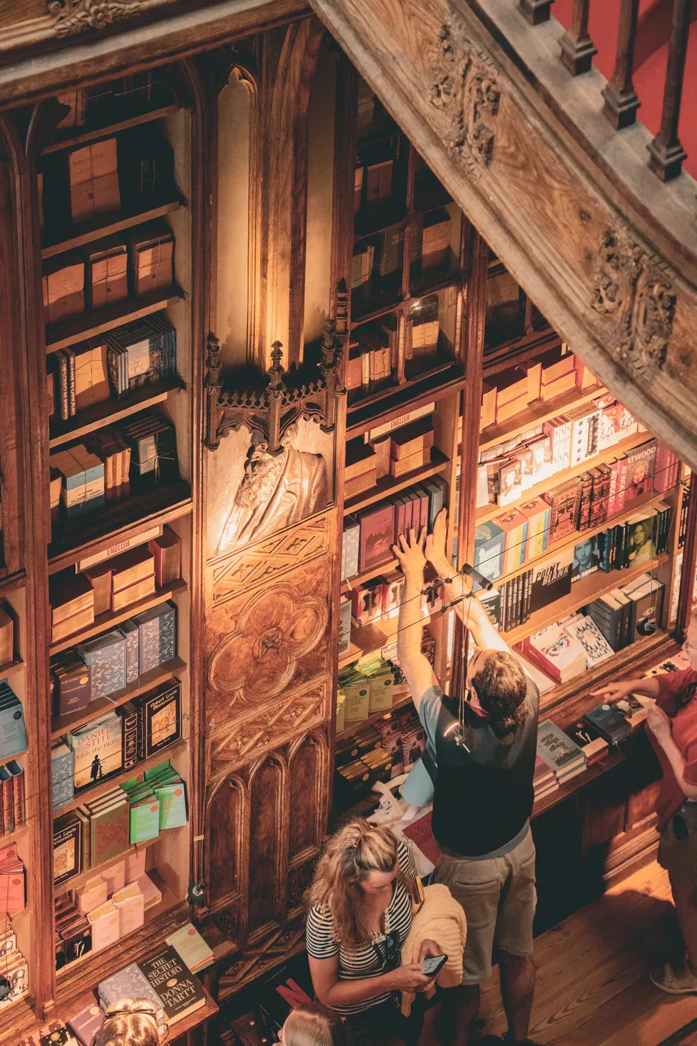 Photographie des rayonnages en bois et de l escalier d une librairie ancienne a Porto.