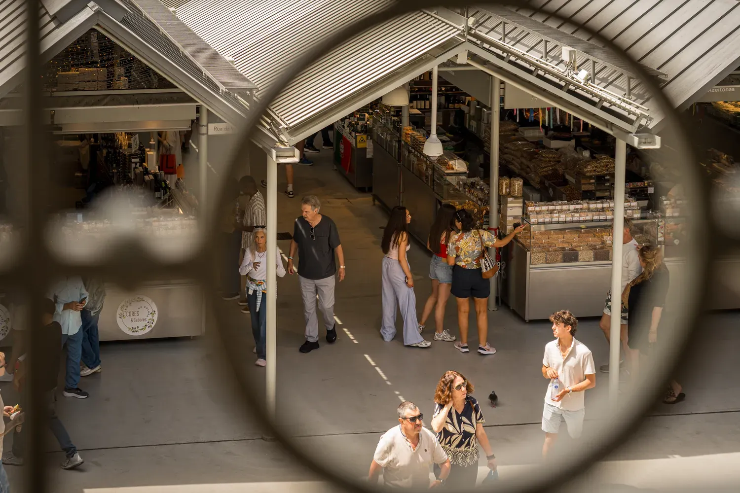 Photographie de passants dans un marche de Porto vus dans un miroir circulaire.