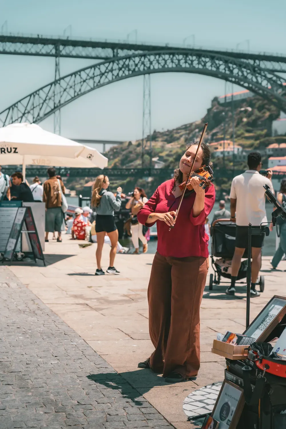 Photographie d une musicienne jouant sur les quais de Porto avec le pont en arriere-plan.