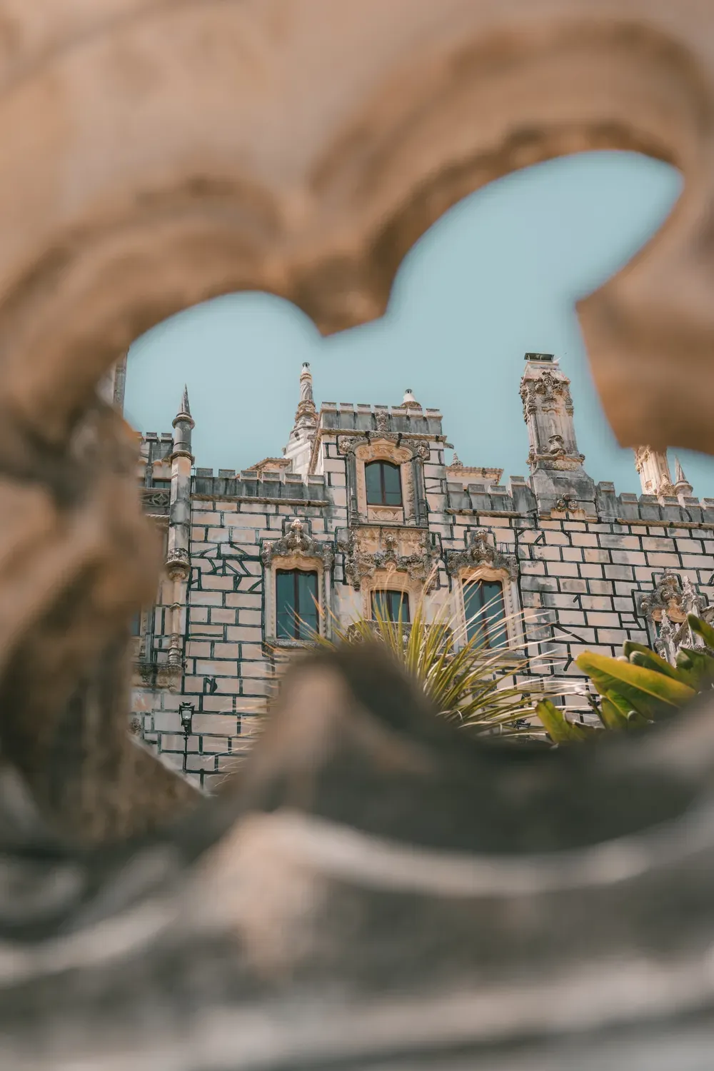 Photographie de la Quinta da Regaleira vue a travers une ouverture de pierre.